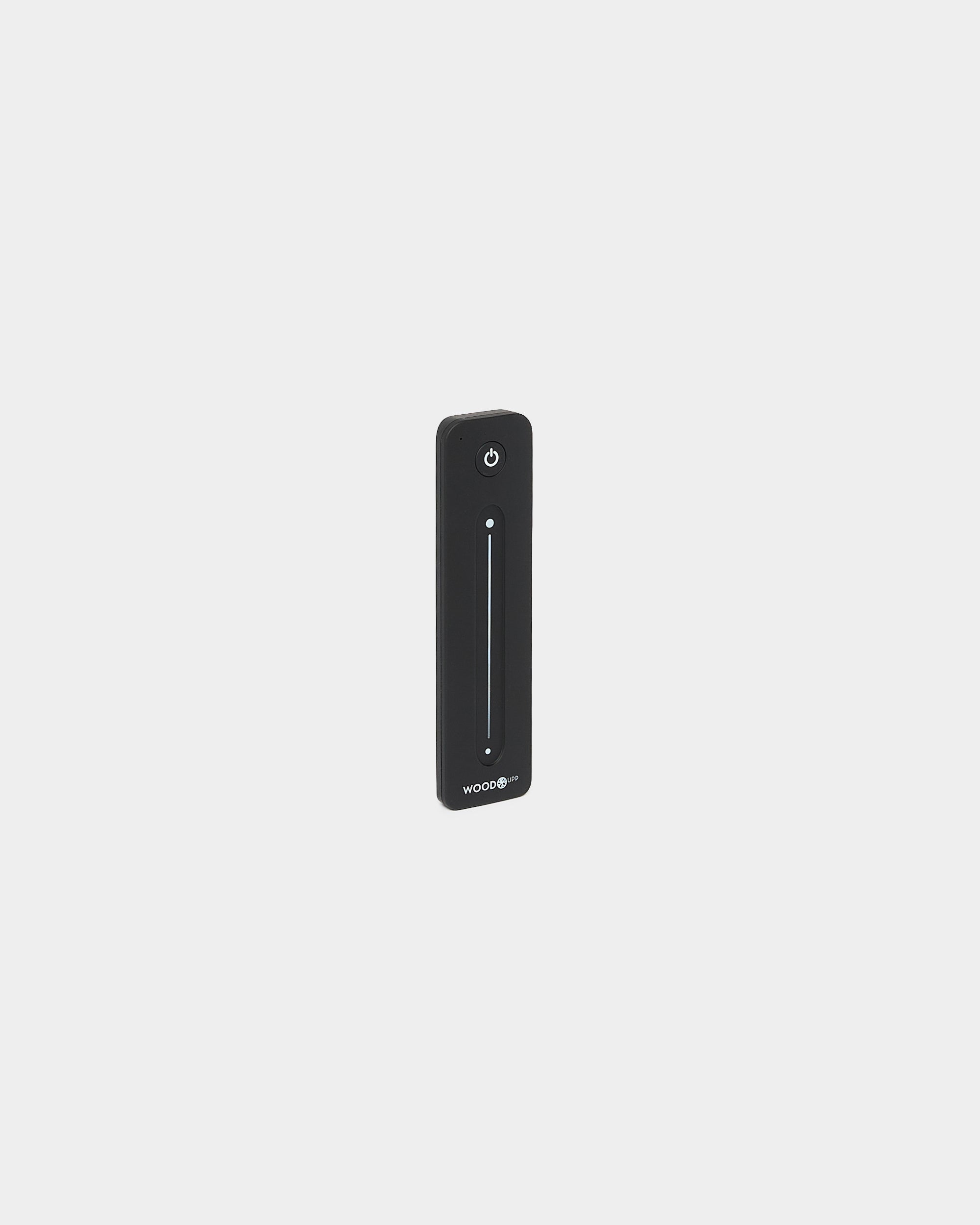 Mando a distancia Slim black WoodUpp Lumi para tiras LED, con vertical deslizador táctil y botón de encendido, compatible con Philips Hue, sobre fondo blanco.